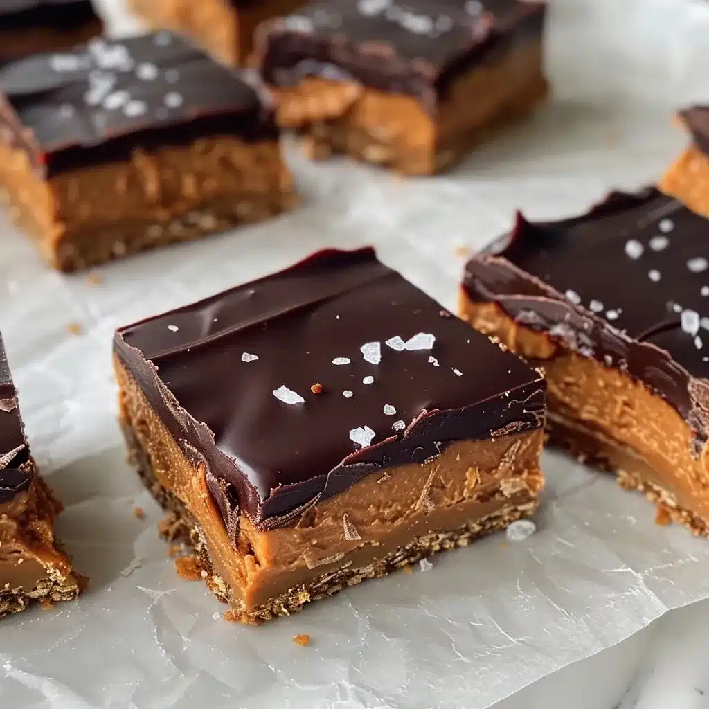Sliced no-bake chocolate peanut butter bars topped with sea salt on parchment paper.