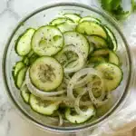 Cucumbers and Onions in Vinegar Recipe: 7 Reasons to Love It 7 Tasty-style overhead photo of cucumber and onion salad in a glass bowl on a white surface with soft natural lighting.