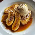 Bananas Foster Recipe Like Grandma Made (But With Flames & Flair) 10 Overhead view of Bananas Foster recipe with halved bananas in caramel sauce and a scoop of vanilla ice cream